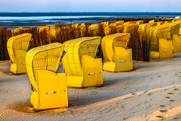 Germany. Cuxhaven. Beach by the Wadden Sea with yellow roofed wicker beach chairs