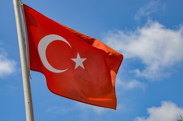 The Turkish flag flutters in the wind against a blue sky

