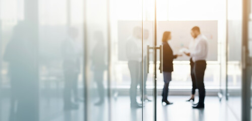 Fototapeta premium Two people talking in a bright modern office space with glass walls, exchanging ideas and engaging in conversation that reflects teamwork and professional communication.