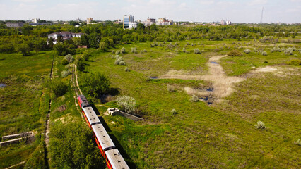Aerial View of Passenger Train Traveling Through Wetland to City