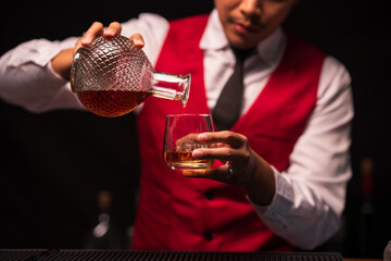 Bartender is pouring whiskey into a glass in a restaurant	