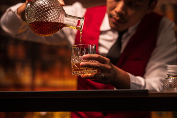 Bartender is pouring whiskey into a glass in a restaurant	
