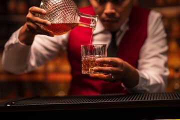 Bartender is pouring whiskey into a glass in a restaurant	