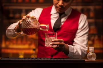 Bartender is pouring whiskey into a glass in a restaurant	