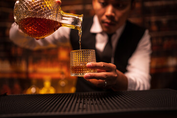 Bartender is pouring whiskey into a glass in a restaurant	