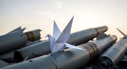 Paper bird symbolizing fragile peace over weapons