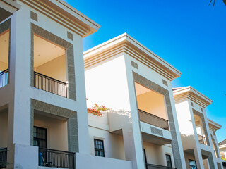 Exterior of building with elements of Art Deco or Mediterranean Revival architecture with clear blue sky background, low angle shot.. Modern apartment building with blue sky