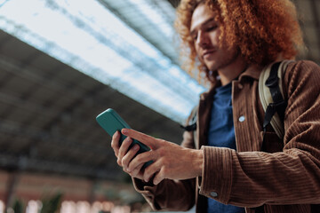 Young student using smart phone app in university hallway