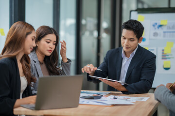 Group of Asian businesspeople sits down for a business investment planning meeting.	
