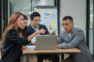 Group of Asian businesspeople sits down for a business investment planning meeting.	