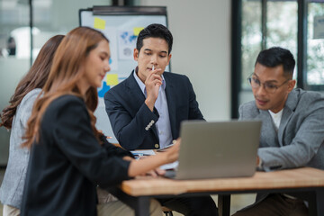 Group of Asian businesspeople sits down for a business investment planning meeting.	