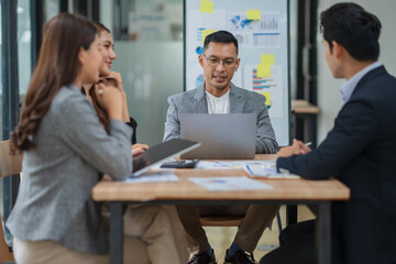 Group of Asian businesspeople sits down for a business investment planning meeting.	