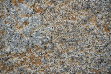 The texture of an old concrete wall. Individual pebbles and hardened cement are visible on the weathered, uneven surface. Background. Close-up. Texture.