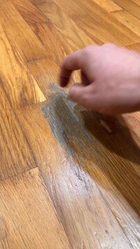A wooden floor with a stain on it. The stain is in the shape of a person. The floor is made of wood and has a brown color