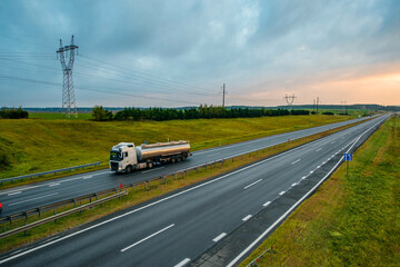a colorful yellow sunrise over a highway with trucks driving along it