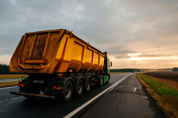 a colorful yellow sunrise over a highway with trucks driving along it