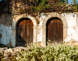 Two weathered wooden doors in an arched stone wall