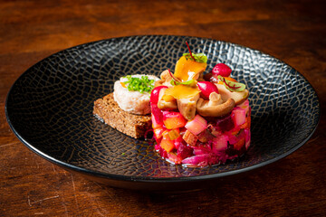 A vibrant salad is beautifully arranged on a black plate, accompanied by a slice of dark bread