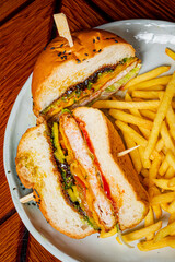 Juicy burger filled with colorful toppings and sides of crispy fries on a casual dining plate