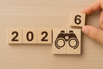 Hand Arranging Wooden Blocks to Form a Year with Binocular Symbol for Future Vision