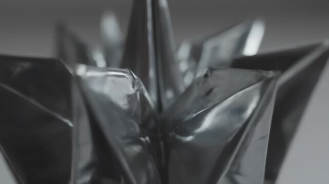 Crumpled metallic sheet forming abstract geometric sculpture, dark elegance.