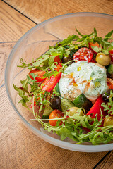A vibrant salad filled with tomatoes, olives, cucumbers, and topped with a creamy dressing