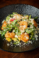 Delicious shrimp salad features fresh greens, cherry tomatoes, and almond slices in a stylish dish