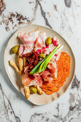 A beautifully arranged platter showcases a variety of cured meats, olives, and crispy snacks