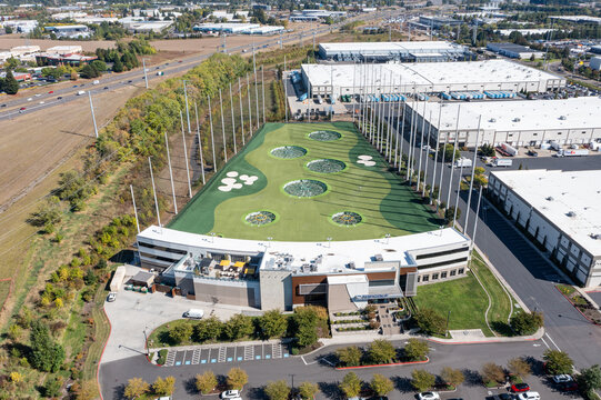 Hillsboro, OR, USA - Sep 22, 2025- High quality aerial drone picture of Topgolf Hillsboro entertainment and driving range facility with golf nets, parking lot and surrounding commercial area 