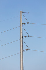 High resolution picture of electric power transmission lines and utility towers in Hillsboro Oregon, showing steel pylons, insulators, and high voltage cables against clear blue sky in industrial area