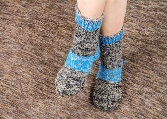 Knitted woolen socks on women's feet. A pair of warm wool socks
