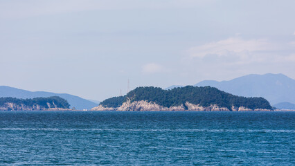 Rocky Forested Island with Mountain Ranges and Blue Sky