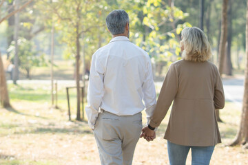 Fototapeta premium Elderly couple lifestyle concept. Husband and wife and sit walking in the park.