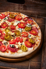Pizza with salami, jalapeno pepper, cherry tomatoes and mozzarella cheese. Soft focus.	