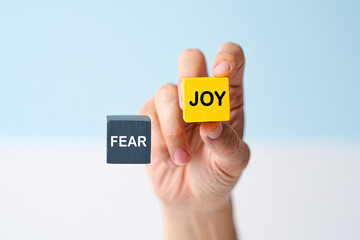 Choosing joy over fear represented with wooden blocks and hand