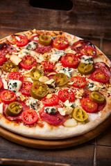 Pizza with salami, jalapeno pepper, cherry tomatoes and mozzarella cheese. Soft focus.	