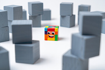 Colorful smiling block stands out among gray cubes for individuality concept