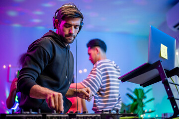 Caucasian young man artist DJ mixing and scratching music mixer controller. 