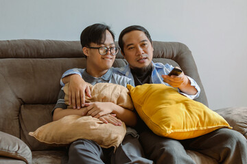 Asian Father and Son with Down Syndrome Enjoying Quality Time Together by Watching TV at Home