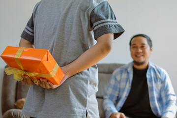 Son Hides a Gift Box Behind His Back for Father on a Special Occasion