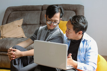 Asian Dad Teaching His Son Through Online Education Using Laptop at Home