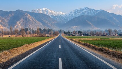 Fototapeta premium Asphalt road stretches towards snowy mountain peaks