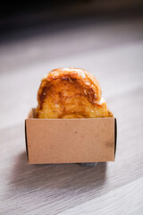 Freshly baked sweet bread roll with golden crust served in brown paper box, ideal for bakery promotion, food packaging design, or cafe menu showcase.