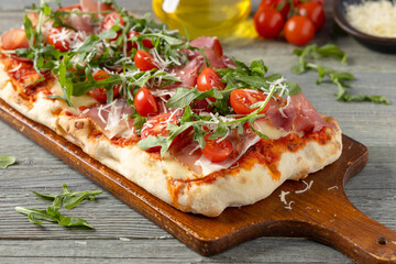 Traditional pinsa with Parma ham, fresh cherry tomatoes and arugula
