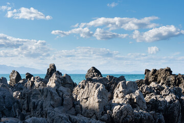 Rocky shore meets the turquoise sea under clouds