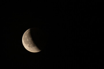 Lunar eclipse beginning close-up right corner sun begins to come on top of moon lunar eclipse black background at night