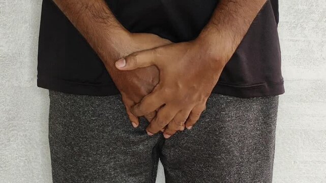 Closeup of indian person hand quickly touch and hold crotch or penis bladder part of body. Uti, kidney problem, discomfort, pain, ache, urinary disease, urinary infection and penile cancer concept.