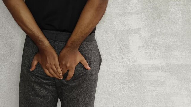 Closeup of person hand touches butt or ass isolated on white background with copy space. Piles disease, diarrhea, pinworm, bottom pain, rectum cancer, constipation or hemorrhoids concept.
