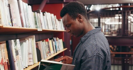 Choosing, books and black man in library at university for research, learning or knowledge. Education, college and African male student with decision on academic information by shelf on campus. - Powered by Adobe