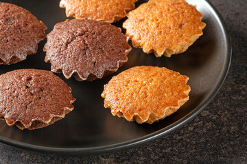 An aesthetic display of lemon and chocolate mini muffins on black plate